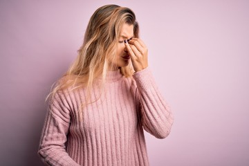 Canvas Print - Young beautiful blonde woman wearing casual pink sweater over isolated background tired rubbing nose and eyes feeling fatigue and headache. Stress and frustration concept.