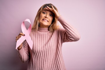 Poster - Young beautiful blonde woman asking for support cancer holding pink ribbon symbol stressed with hand on head, shocked with shame and surprise face, angry and frustrated. Fear and upset for mistake.