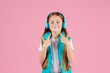 © Ilnur - A little girl with headphones explodes pink chewing gum on a pink background