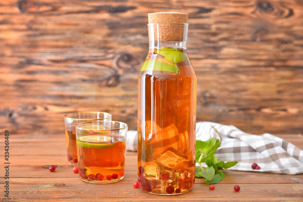 Bottle and glasses of tasty cold tea on table