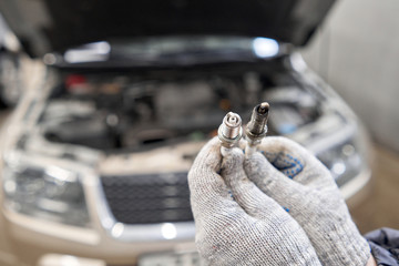 Old and new spark plugs. Comparing spark plugs the maintenance of the engine, on the hands of a mechanic.