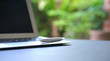 © sinseeho - Writing pen on top of computer laptop with green nature background.