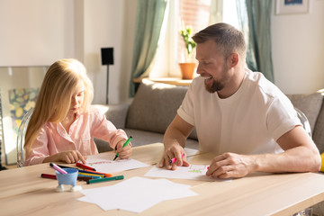 Wall Mural - Cute little pre-elementary schoolgirl and her father drawing together at home