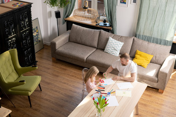 Wall Mural - Young man and his cute little daughter in casualwear drawing together