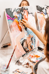 A young woman painstakingly draws her picture with brushes on easels in an art class. learning to draw , art school, creativity and the concept of people