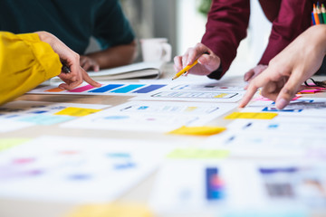 Close up ux developer and ui designer brainstorming about mobile app interface wireframe design on table with customer brief and color code at modern office.Creative digital development agency.panning