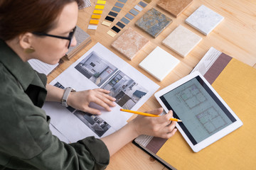 Young female designer of interior looking through electronic sketches of flat