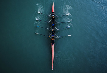 kayak from above with 4 rowing people. blue and aqua water background. sport and moving concept. red