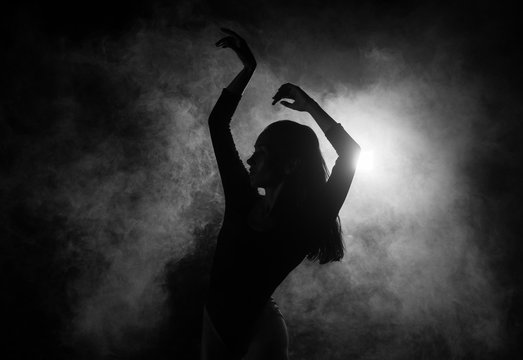 Fototapete - Female silhouette dancing in shadow and smoke