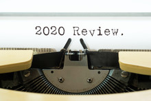 2020 Review Word Typed On A Yellow Vintage Typewriter. Business Concept.
