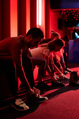 Sticker - Row of young casual friends sitting on bench and putting on bowling shoes