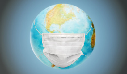 health care, virus and pandemic concept - earth planet globe in protective medical mask over blue background