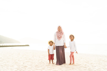 Asian kids having leisure time with their mother at the beach.