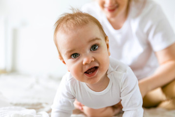 a nine-month-old baby crawls on the floor, looks at the camera with an interest and delight