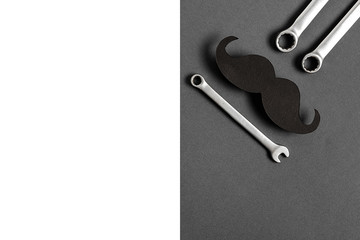 Wall Mural - Fathers Day mockup with retro stylish black funny paper moustache and combination wrenches on grey background with copy space. Flat lay, top view, minimal composition