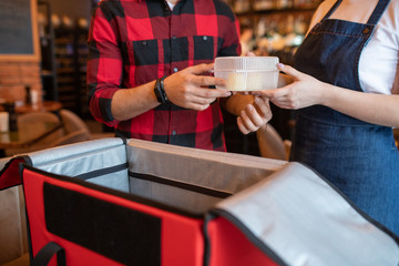 Wall Mural - Waiter of cafe passing plastic container with order of client to courier