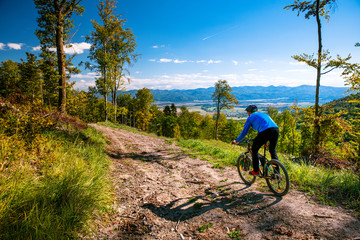 Wall Mural - Mountain biking man riding downhill on bike at autumn mountains forest landscape. Outdoor sport activity. Colorful nature.