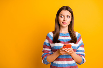 Poster - Portrait of her she nice attractive curious pensive bewildered brown-haired girl holding in hands cell thinking creating plan isolated over bright vivid shine vibrant yellow color background