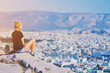 © raisondtre - Young tourist woman sitting on top of mountain and looking at a beautiful landscape cityscape Athens Greece. Adult girl tourist relax on hill overlooking Athens in summer. Famous Athens city in Europe