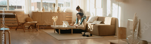 Fotografía Mother working from home, having a phone call, while her daughter distracts her