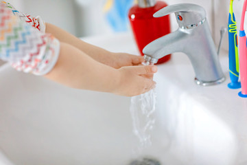 Closeup of little toddler girl washing hands with soap and water in bathroom. Close up child learning cleaning body parts. Hygiene routine action during viral desease. kid at home or nursery.