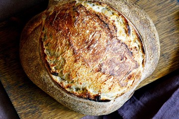 Homemade Freshly Baked Country Bread  made from wheat and whole grain flour on a gray-blue background. French Freshly baked bread. Slicing homemade bread 