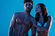 sensual girl in white lingerie embracing sexy man looking at camera isolated on blue