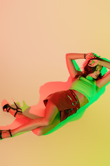 Wall Mural - top view of attractive, trendy girl lying with closed eyes on yellow background with green and red shadows