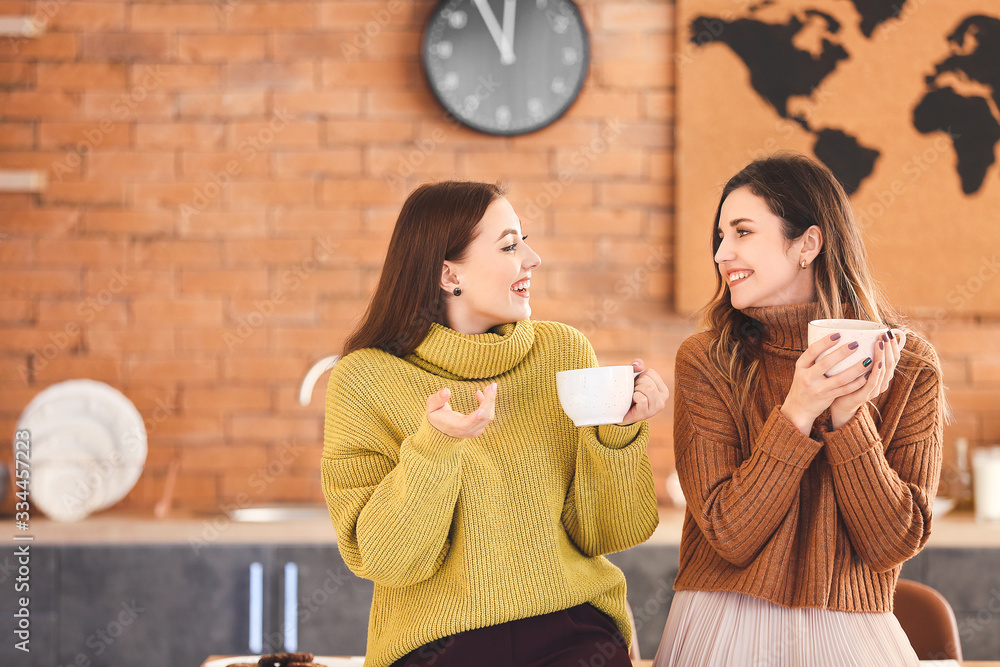 Young women drinking tea in kitchen