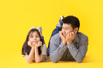 Wall Mural - Happy Asian man and his little daughter on color background