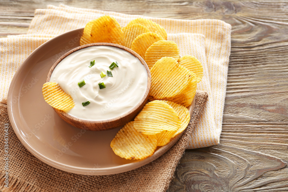 Tasty sour cream and potato chips on table