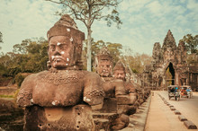 Mythic Statues Line The Causeway Over A Moat Leading To The Gate Of Angkor Thom, Great City Of Cambodia. 12th Century Artworks Near The Gate Of Historical Landmark. UNESCO World Heritage Site