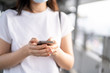 © DG PhotoStock - Young Asian woman using a touch screen smartphone while walking at the crowded place. Woman addicted social network all of the day. Woman talk to her friend by using smartphone. Copyspace in photo.