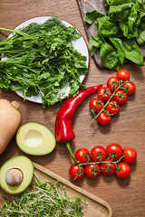 Canvas Print - Top view of vegetables, avocado halves, greenery, microgreens and basil leaves on cutting boards on wooden background