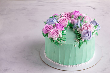  Tasty cake with cream roses for wedding, birthday. Beautiful, fashionable cake. Turquoise on a marble table. Copy space.