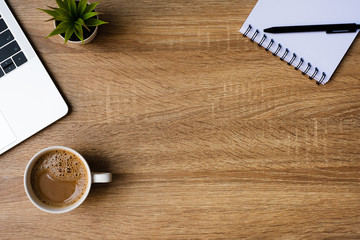 desk office with laptop, blank notepad, coffee cup and pen on wood table. flat lay top view copy spc