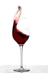 Close up view of splashing red wine in glass isolated on white background. 