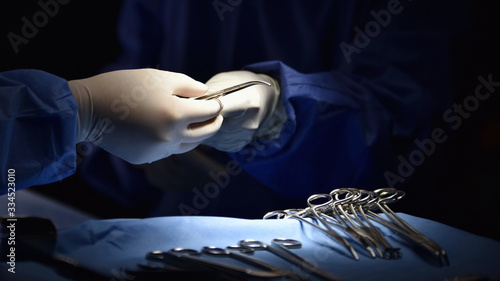 Fototapeta na szkło instrument chirurgiczny leżący na stole, podczas gdy grupa chirurgów pracuje w sali operacyjnej w szpitalu, nagły przypadek, operacja, technologia medyczna, opieka zdrowotna rak i leczenie chorób