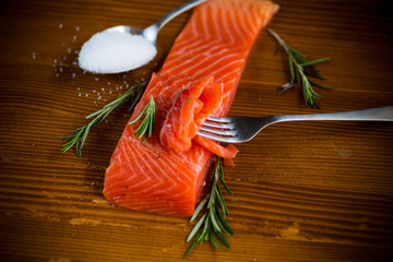 salty red fish on a fork, wooden background