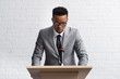 © LIGHTFIELD STUDIOS - serious african american business speaker on tribune with microphone in conference hall