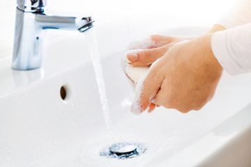 Wall Mural - Woman use soap and washing hands under the water tap. Hygiene concept hand detail.