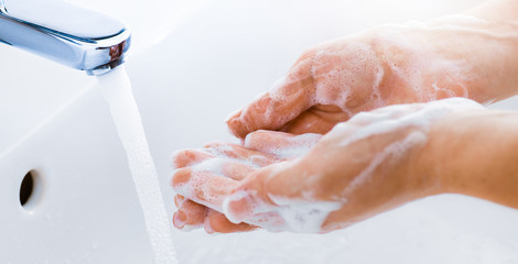 Wall Mural - Woman use soap and washing hands under the water tap. Hygiene concept hand detail.