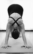 © Josu Ozkaritz - Woman in overalls doing adho mukha svanasana yoga pose in bright room studio. Female yogi in downward facing dog asana. Natural light, workout, minimal concepts. Black and white vertical photography