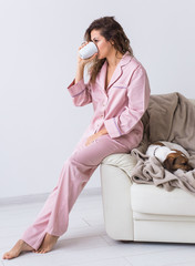 Wall Mural - Young attractive woman dressed in beautiful colorful pajama posing as a model in her living room. Comfortable sleepwear, home relaxation and female fashion concept.