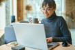 © vitaliymateha - Young smiling business woman in spectacles working on portable laptop computer. Female copywriter sitting at desk and typing on keyboard, working on project, writing down ideas into netbook