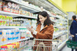 © Robert Daly/Caia Image - Smiling woman reading label on container in supermarket