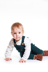 Wall Mural - a cute one-year-old child stands in a White Studio. He is dressed in a white shirt and overalls