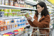 © Robert Daly/Caia Image - Young woman reading label on container in supermarket