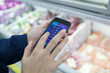 © Sam Edwards/Caia Image - Close up woman using smart phone shopping list app in supermarket