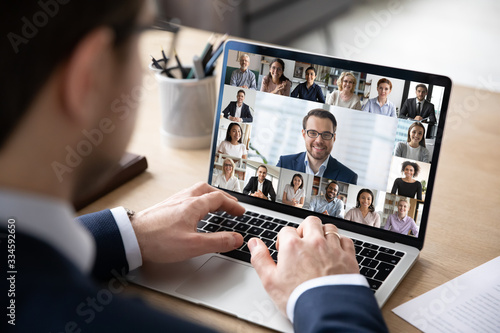Fotografía Rear view of businessman speak on web conference with diverse colleagues using l